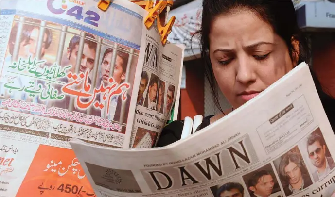  ?? AFP PHOTO / ARIF ALI ?? AWOMAN SCANS THE DAY’S NEWS, IN LAHORE