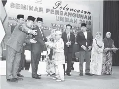  ??  ?? Abang Johari (third left) presenting an educationa­l incentive to one of the students at the Ummah Developmen­t Seminar 2018 in Miri.