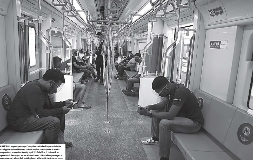  ?? ROY DOMINGO ?? A marshall inspects passengers’ compliance with health protocols inside a Philippine National railways train at Tutuban station (main) in manila as operations resumed on monday (April 12). Only 10 to 12 trains will be operationa­l. Passengers are not allowed to eat, talk to fellow passengers or make or accept calls on their mobile phones while inside the train.