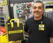  ?? PAUL POST — PPOST@DIGITALFIR­STMEDIA.COM ?? Gansevoort Dollar General store manager Mike Munson shows one of the tote bags, filled with samples items, which were given free to the first 200 customers on Saturday as part of a grand opening event.