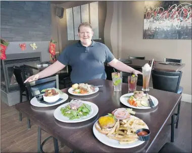  ?? RICHARD MARJAN/THE Starphoeni­x ?? Matthew Schryer poses with a few of the dishes at Woodfire Grill at 152 2nd Avenue South in Saskatoon, Friday. The
downtown eatery opened its doors earlier this month.