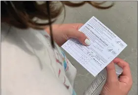  ?? (AP/Angie Wang) ?? Jane Ellen Norman, 12, holds vaccinatio­n cards for her and her 14-year-old brother Owen outside Mercedes-Benz Stadium in Atlanta after receiving their covid-19 shots in May. As more places are requiring proof of vaccinatio­n, many people opposed to the vaccine are purchasing fake vaccinatio­n cards to get around the rules.