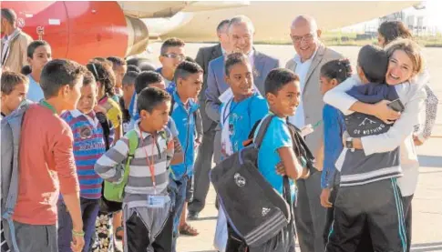  ?? F. HERAS ?? La consejera de Familia abraza a uno de los niños junto Carnero ayer en el aeropuerto de Villanubla