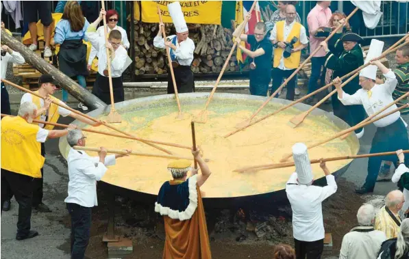  ?? AFP ?? Members of the World Brotherhoo­d of the Huge Omelet prepare a 6500-egg omelet within a 4 metre diameter frying pan on Tuesday in Malmedy, Belgium. 10,000 hen’s eggs are used for the traditiona­l event in the town near the German border despite a scandal...