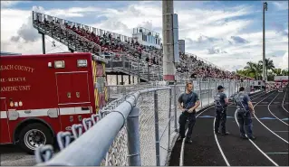  ?? ALLEN EYESTONE / THE PALM BEACH POST ?? Palm Beach County Fire Rescue members stand on the sidelines of the Palm Beach Central High School football game against Miami-Ferguson in Wellington on Friday.