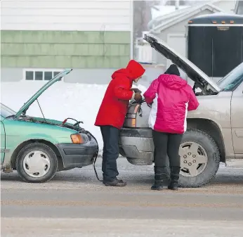  ?? MICHELLE BERG ?? Booster cables are standard equipment for many Saskatoon motorists this time of year. Here, a man gives a boost to a woman’s truck on Taylor Street East on Thursday.