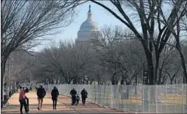  ?? REBECCA BLACKWELL/AP ?? People walk past a section of the National Mall near the Capitol where workers were still dismantlin­g inaugurati­on installati­ons Saturday in Washington.