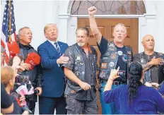  ?? CAROLYN KASTER/ASSOCIATED PRESS ?? President Donald Trump stands in the rain with members of Bikers for Trump and supporters as they say the Pledge of Allegiance Saturday at the clubhouse of Trump National Golf Club.