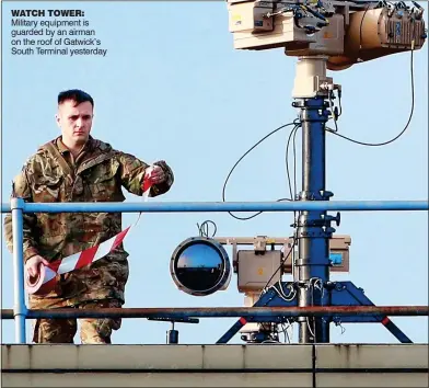  ??  ?? WATCH TOWER: Military equipment is guarded by an airman on the roof of Gatwick’s South Terminal yesterday