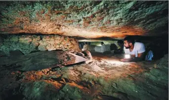  ?? MOHAMED ABD EL GHANY / REUTERS ?? An Egyptian antiquitie­s worker inside the recently discovered burial site in Minya, Egypt, on Saturday.