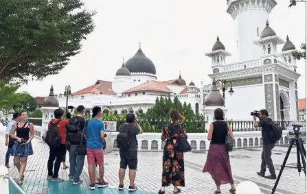  ??  ?? Capturing the moment: The participan­ts taking photos during the walk along the Street of Harmony in Jalan Masjid Kapitan Keling, George Town.