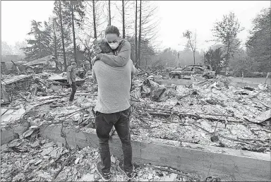  ?? [JEFF CHIU/THE ASSOCIATED PRESS] ?? Todd Caughey hugs his daughter Ella as they visit the site of their home in Kenwood, Calif. The house, and hundreds of others, was destroyed by wildfires on Monday.