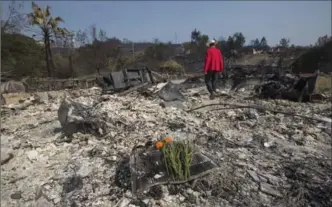  ?? DAVID MCNEW, GETTY IMAGES ?? Flowers mark the spot where his father died as Mike Rippey walks through the ruins of the house of Charles, 100, and Sara Rippey, 98, who were killed in the Atlas Fire just after it began near Napa, Calif.