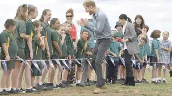  ?? — AFP ?? Prince Harry and his wife Meghan are greeted by schoolchil­dren following the couple’s arrival at Dubbo Regional Airport in Dubbo on Wednesday.