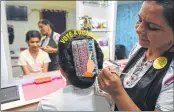  ?? AFP ?? Beautician Sejal Rao (R) gives finishing touches as she paints 'Electronic Voting Machine' (EVM) on the hair of a girl in Guj.