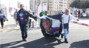  ?? (Marc Israel Sellem/The Jerusalem Post) ?? LIKUD ACTIVISTS carry a poster of Miri Regev on Tuesday, the day of the Likud primaries.