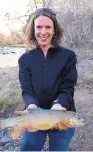  ?? COURTESY OF NEW MEXICO DEPART-
MENT OF GAME AND FISH ?? Jill Wick, Gila trout biologist with the New Mexico Department of Game and Fish, displays one of the fish. The Gila trout is being restored to the Gila and San Francisco river drainages of New Mexico and Arizona.