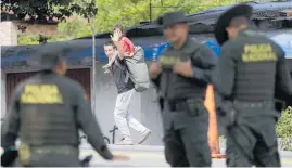  ?? Photo / AP ?? A Venezuelan migrant carrying his daughter waves to Colombian police in Los Patois, near Cucuta.