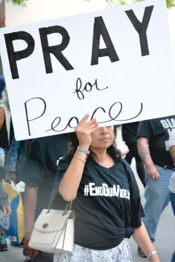  ?? JOHN W. FOUNTAIN ?? A woman hoists a sign at a recent “Friday Night Peace Walks” event by the Faith Community of St. Sabina. The walks are held annually from the start of summer until the end.