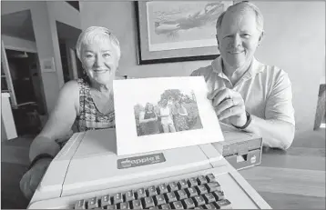  ?? ELAINE THOMPSON/AP ?? Kathy and Stephen Dennis show a photo of grandchild­ren and phones as they display a 1980s-era Apple II+ computer.