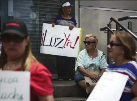  ?? CARLOS GIUSTI — THE ASSOCIATED PRESS ?? Residents from Yabucoa protest outside the Electric Power Authority office, demanding the reestablis­hment of electricit­y. The sign reads in Spanish “Light now!”
