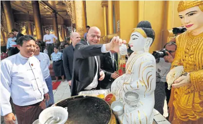  ??  ?? Fifa president Gianni Infantino pours water over a Buddha image in Yangon on Friday as president of the Myanmar Football Federation Zaw Zaw, left, looks on.