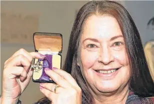  ?? JIM WELLS ■ POSTMEDIA ?? Tracey Scott shows a Memorial Cross medal which was among antique family photos returned in Calgary on Sunday. The photos and war medals were found in a donation to Goodwill and after some investigat­ion by Goodwill staff, the items were returned to Scott and her family.