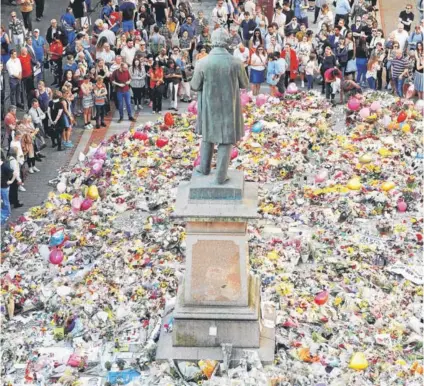  ?? FOTO: REUTERS ?? ►► Decenas rinden tributo a las víctimas en la plaza St Ann’s, ayer en Manchester.