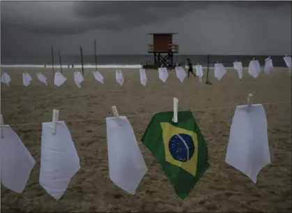  ?? AP PHOTO/BRUNA PRADO ?? A Brazilian flag hangs on a clotheslin­e on Copacabana beach amid white scarves that represent those who have died of COVID-19 in Rio de Janeiro, Brazil, on Oct. 8.