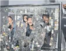  ?? ?? Koffi (right) poses for a photo with visitors behind his artwork made with used telephone keyboards during his show’s opening at the Donwahi foundation.