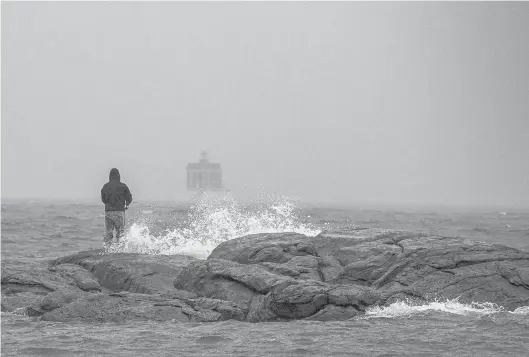  ?? MARK MIRKO PHOTOS/HARTFORD COURANT ?? Adam Lurch fishes from the rocks off Eastern Point along Long Island Sound in Groton on Oct. 26 as a nor’easter was forecast to bring heavy rain and strong winds. Climate change and rising sea levels are threatenin­g coastal towns like Groton.