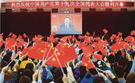  ?? AFP PIC ?? College students waving national flags as they watch the opening of the 19th Communist Party Congress in Huaibei, Anhui province, China, yesterday.