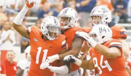  ?? RYAN M. KELLY/GETTY IMAGES ?? Charles Snowden, left, celebrates a sack with Virginia teammates during the Cavaliers’ 27-3 victory against Louisville in the ACC opener for both teams at Scott Stadium.