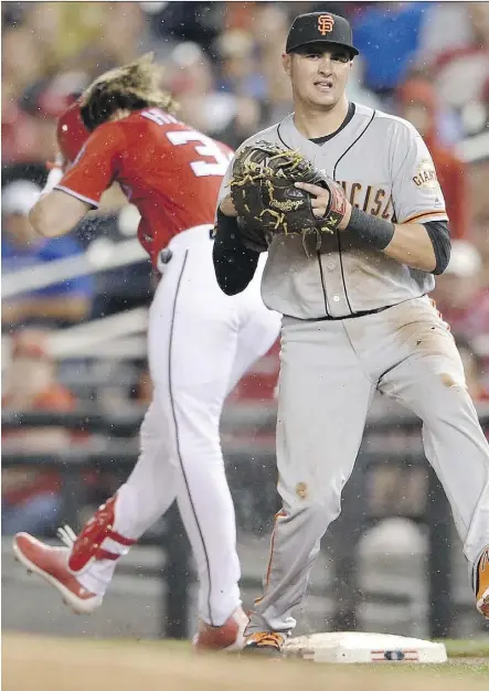  ?? NICK WASS/THE ASSOCIATED PRESS ?? Washington Nationals outfielder Bryce Harper, left, slides his foot across a damp first base bag on Saturday in Washington, D.C. Harper suffered a significan­t bone bruise on the play.