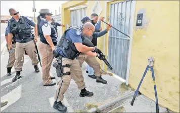  ?? PICTURE: HENK KRUGER ?? JOINT EFFORT: Metro police breaking open a door to a house in Cape Town. The ANC’s national general council set for October will discuss combining the police service and metro police department­s.