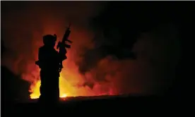  ?? Corum/US Military/AFP/Getty Images ?? A solider in front of a burn pit near Camp Fallujah, Iraq, in 2006. Photograph: Samuel D