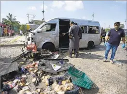  ?? Fareed Khan Associated Press ?? INVESTIGAT­ORS examine a van that was targeted in a suicide attack Friday in Karachi, Pakistan. Five Japanese nationals who were in the van were unharmed.