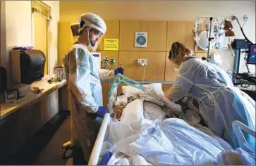  ?? Francine Orr Los Angeles Times ?? NURSES ANTHONY STAMEGNA, left, and Virginia Petersen reposition a COVID- 19 patient at Providence Holy Cross Medical Center in Mission Hills on Dec. 3. Medical systems statewide are feeling intense pressure.