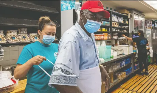  ??  ?? Co-owner Sophy Agelopoulo­s gives Edwin Semper a hand with his apron. The owners “put in the same work and hours as we do,” says Semper, the deli’s longest-serving employee.