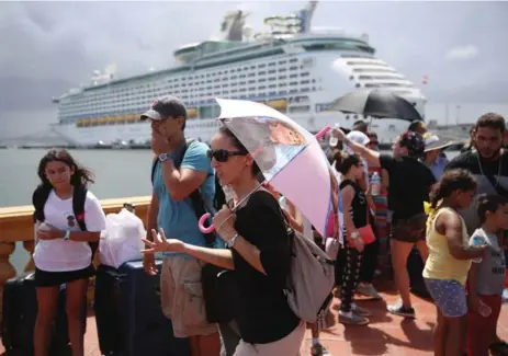  ?? JOE RAEDLE/GETTY IMAGES ?? People in San Juan try to stay cool as they line up to get onto a Royal Caribbean cruise ship that was due to take evacuees from Puerto Rico to Florida.