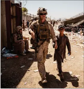  ?? (AP/U.S. Marine Corps/Staff Sgt. Victor Mancilla) ?? A U.S. Marine with the Special Purpose Marine Air-Ground Task Force-Crisis Response-Central Command escorts a child Tuesday at the Kabul airport as evacuation­s from Afghanista­n continue. About 21,600 people were flown out in the 24-hour period that ended early Tuesday, the White House said. The U.S. has helped evacuate more than 58,000 people since Aug. 14.