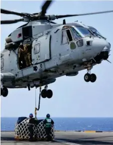  ?? (Photos: Vayu) ?? Royal Navy Air Engineers disconnect stores from a Merlin Mk 4 helicopter during vertical replesnish­ment.