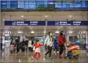  ?? MARK SCHIEFELBE­IN — THE ASSOCIATED PRESS ?? Travelers in face masks walk past a display board showing a canceled flight from Wuhan at Beijing Capital Internatio­nal Airport in Beijing on Thursday.