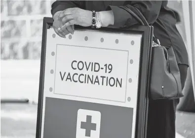  ?? TNS ?? A woman leans on a COVID-19 vaccine registrati­on sign at a back-to-school vaccine fair in Baltimore on Aug. 26.