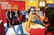  ?? AP ?? Conference attendees pose for a photo next to a statue of former president Donald Trump at the merchandis­e show at the Conservati­ve Political Action Conference.