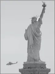  ?? AP/JULIO CORTEZ ?? A Marine attack helicopter makes a pass by the Statue of Liberty as seen from Liberty State Park in Jersey City, N.J., on Wednesday.