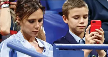  ??  ?? Eyes down: Mother and son take a break to check their mobile phones