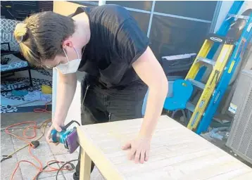  ??  ?? Chrys Diaz, whose family escaped a house fire two years ago, works at sanding down the dining room table he made and donated to the Sweet Dream Makers organizati­on.