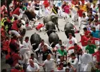  ?? AP PHOTO/ALVARO BARRIENTOS ?? Revellers fall next to Miura's fighting bulls during the running of the bulls at the San Fermin Festival, in Pamplona, northern Spain, Friday. Medical officials in Spain say that the bull run on the final day of the San Fermin festival has left six...
