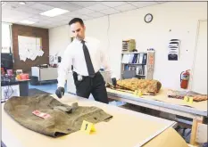  ??  ?? Mitchell Warwick looks over a military- style duffel bag and other evidence at police headquarte­rs in Milford. The bag is evidence in the killing of an unidenfied man whose body was found in 1994.
